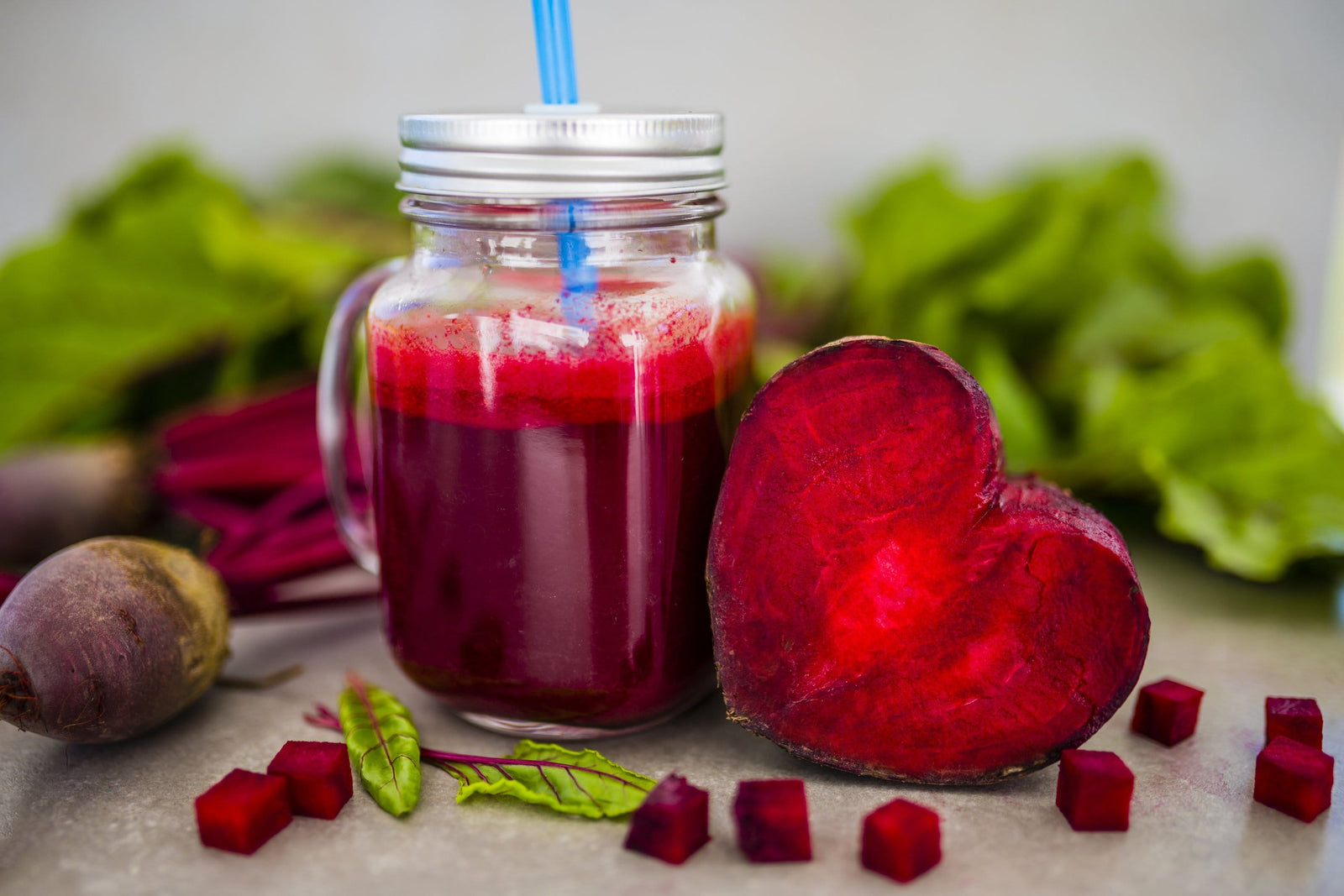 Beetroot in heart shape next to a glass of beetroot juice