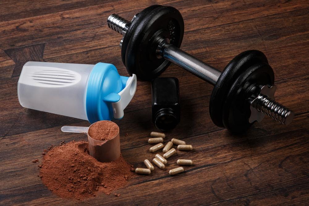 Dumbbell, shaker, a scoop of protein powder and a few pills