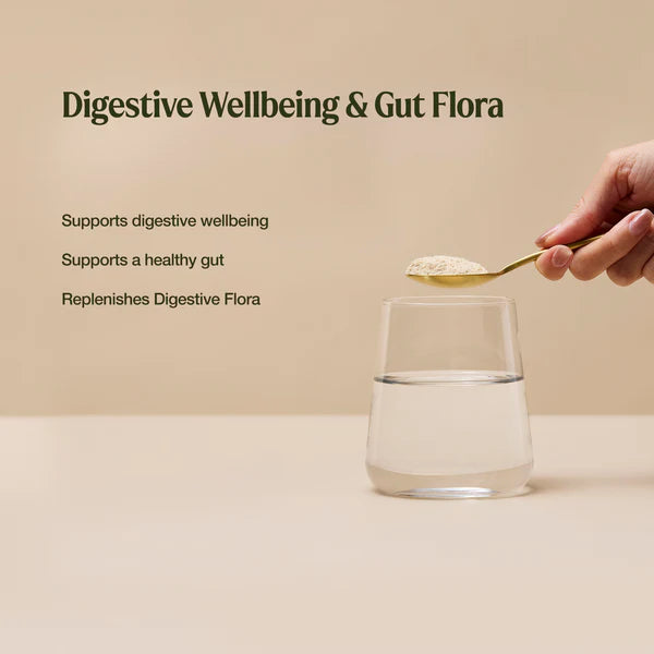 Spoon with probiotics powder over a glass of water on a beige background, promoting digestive wellbeing and gut flora.