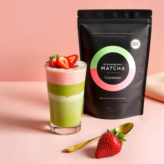 Strawberry matcha latte with a package of Tropeaka Strawberry Matcha on a pink background