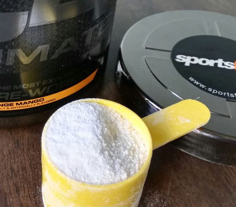 A yellow scoop with protein powder and a container + lid in the background