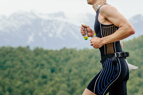 Runner with an Energy Gel in his hands and mountains in the background