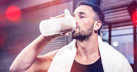 Men with a towel around his neck having a protein shake