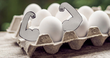 Tray of white eggs and one of them got crafted muscly arms.