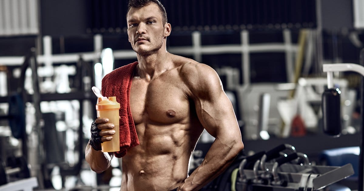Muscular man holding an orange protein shaker.