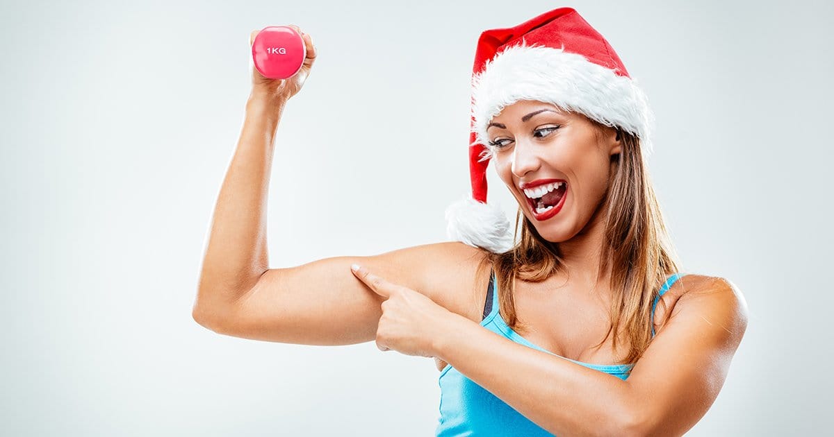 Women with a Christmas hat and holding up a dumbbell pointing at her biceps.