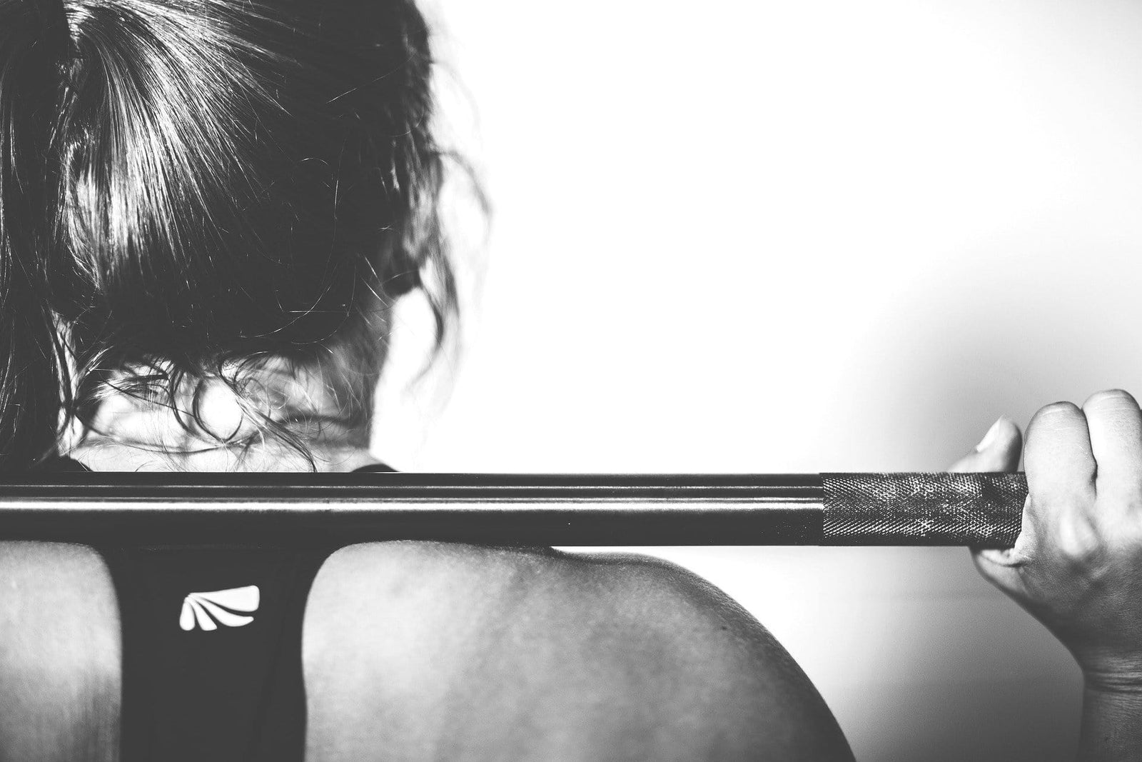 Back view from a women holding a barbell up