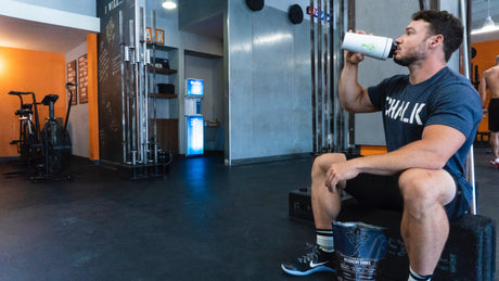 A man seated in the gym drinking a protein shake