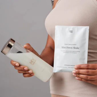 Person holding a shake container and a package labeled 'Slim Down Shake' against a neutral background
